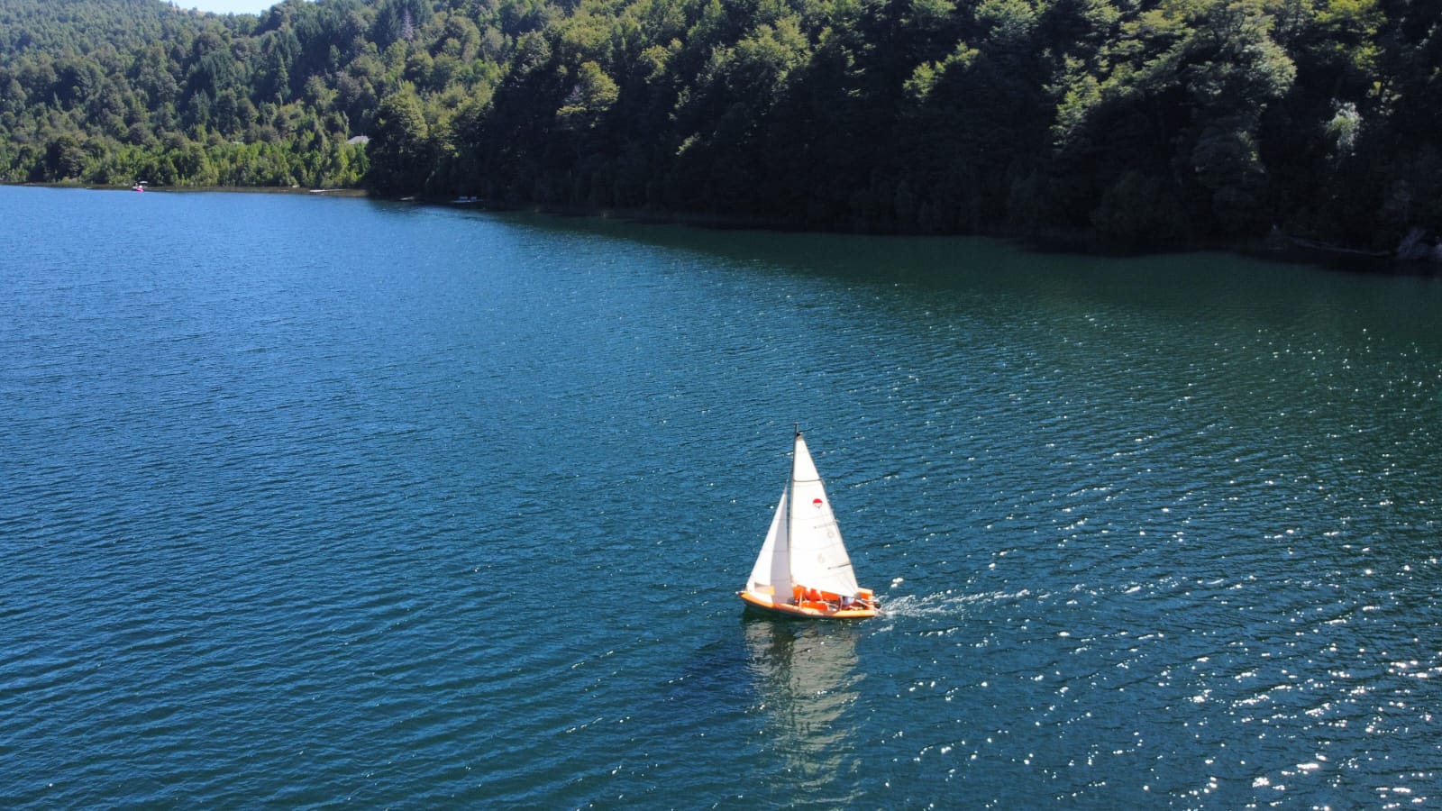 Velero en el Lago Tinquilco visto desde el aire con bosque nativo en las orillas